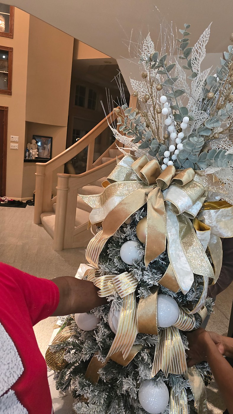 Close up of a gold and white Christmas tree being styled by hand