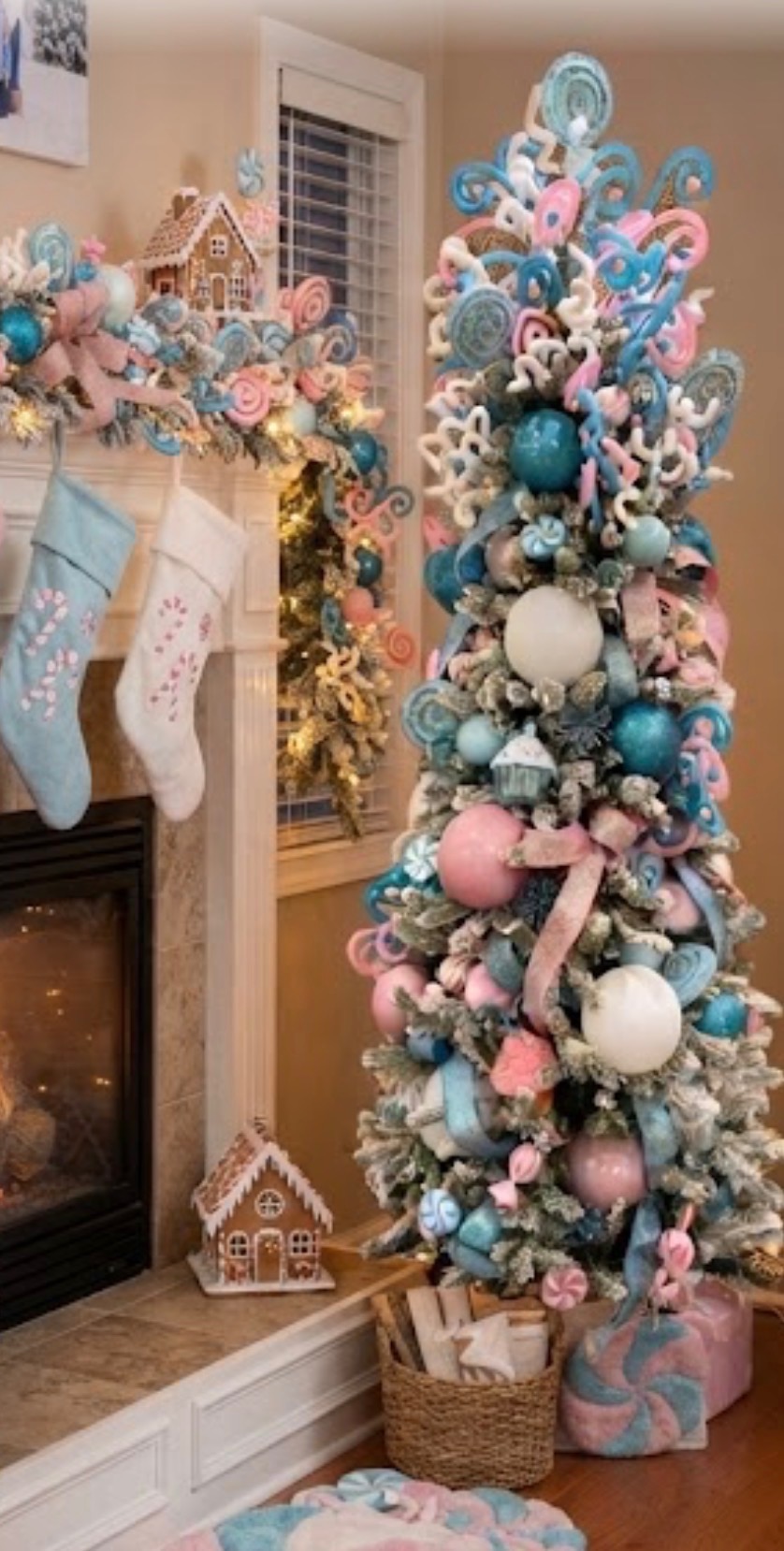 Pastel pink and blue candy-themed Christmas tree with gingerbread houses, mantel garland, and stockings