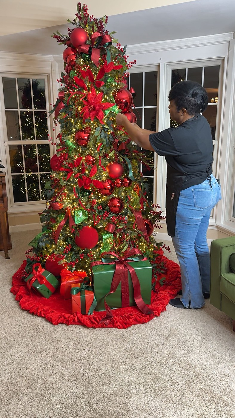 Chymica styling a red and green Christmas tree in a client's home